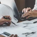 Designers reviewing technical drawings beside a hard hat