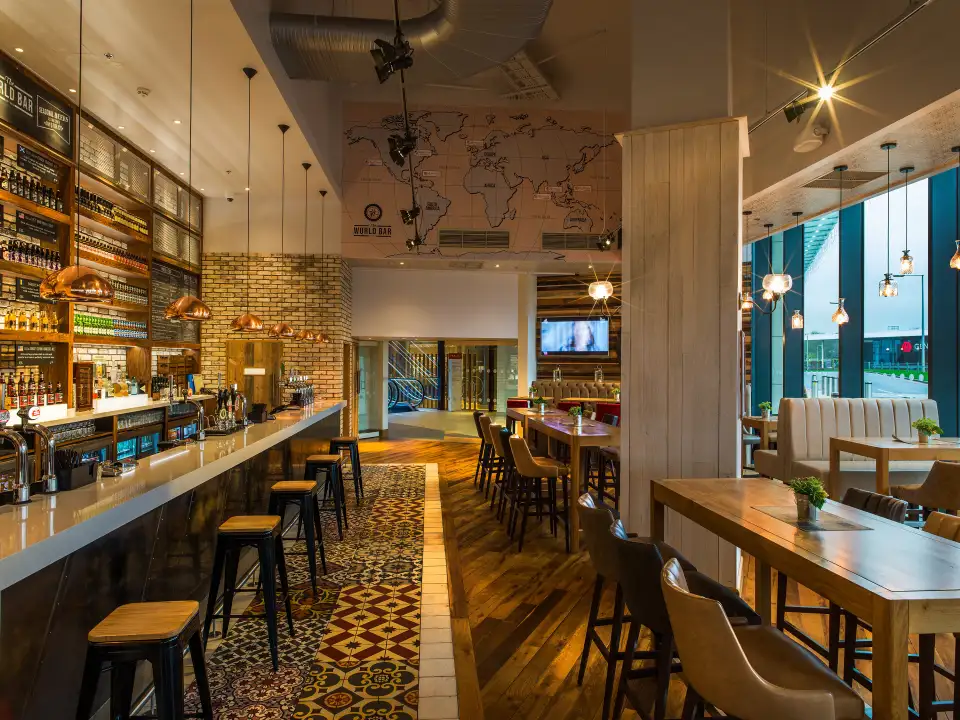 Bar with a timber counter, bar stools and back-lit shelving