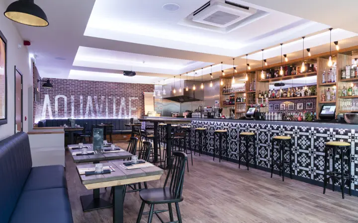 Aquavitae cocktail bar with a patterned tiled bar front and booth seating