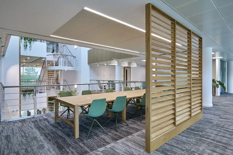 Meeting area with a timber table, teal chairs and a slatted timber screen