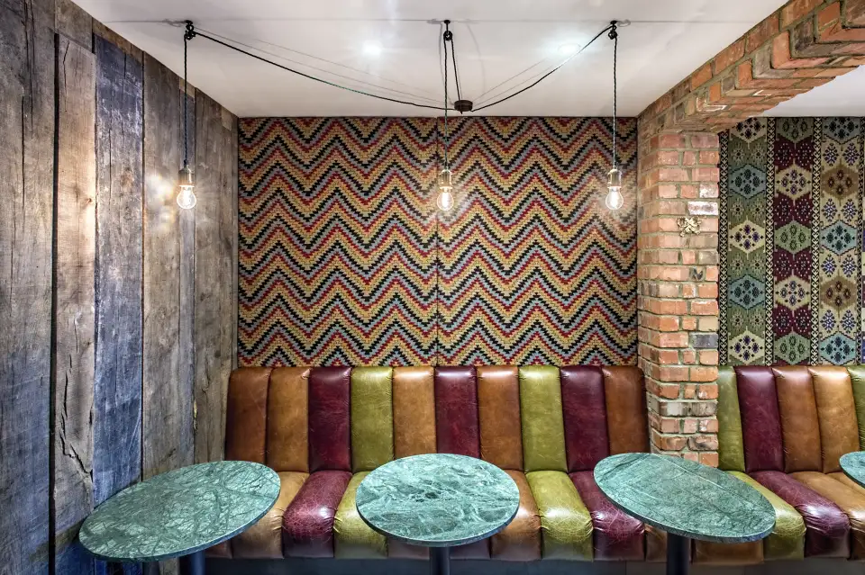 Multicoloured leather bench seating with green tables at A Wanted Man