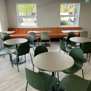 Amiosec break-out space with green chairs and round tables