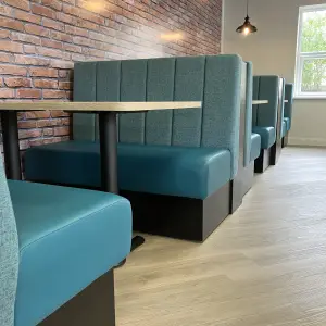 Amiosec break-out booth seating with teal upholstery and a brick-effect wall
