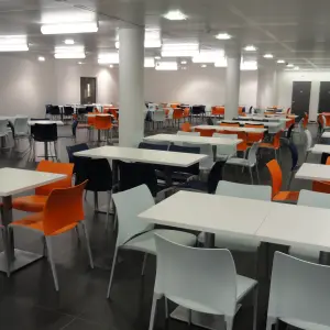 Dining area with white tables and orange chairs at Corsham CDP