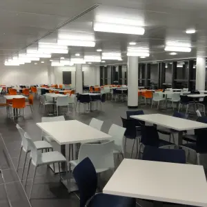 Dining area with white tables and colourful chairs at Corsham CDP