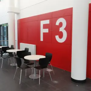 Breakout area with café tables beside a red F3 sign at Corsham CDP
