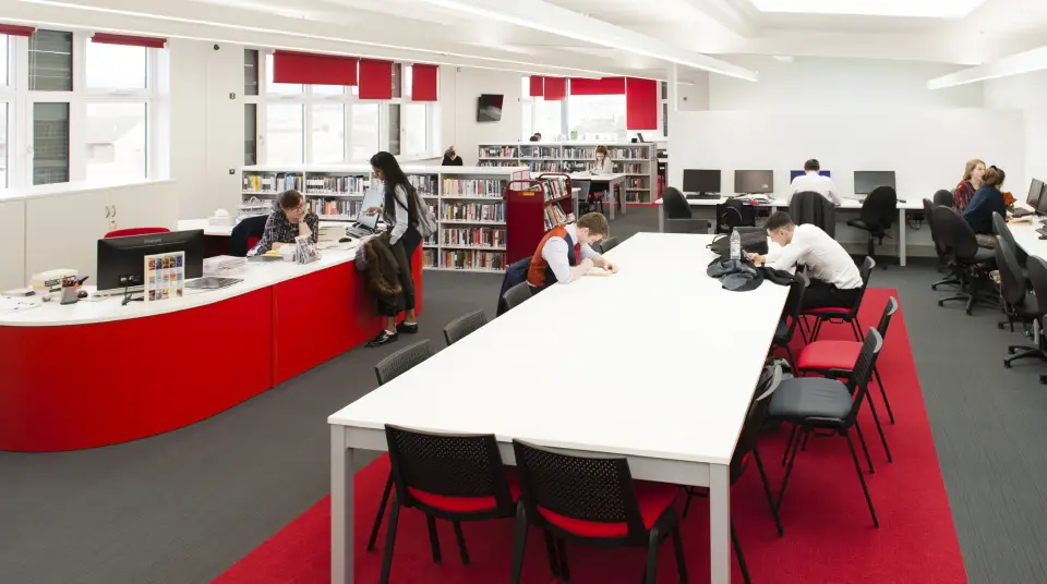 Pate&rsquo;s Grammar School library with a red issue desk and study tables