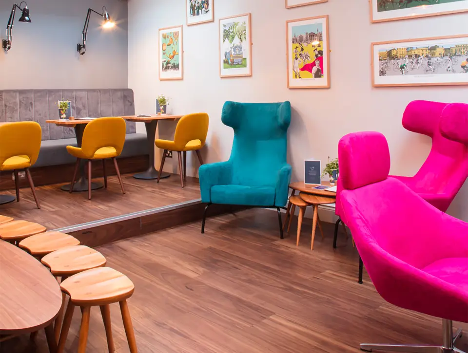 The Find lounge with pink and teal armchairs and timber tables