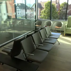 Waiting area with grey beam seating and green armchairs at The Wilson Health Centre