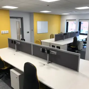 Staff office with desks and a yellow feature wall at The Wilson Health Centre