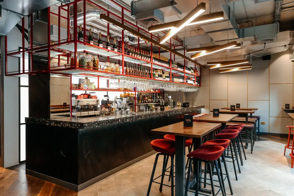 VQ Aldgate bar with red bar stools and copper shelving