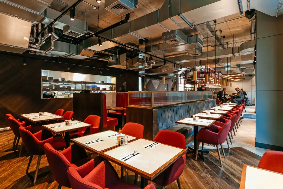 VQ Aldgate dining area with red chairs and timber tables